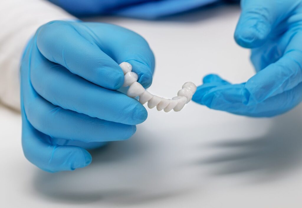 stomatologul ține în mâini o coroană dentară